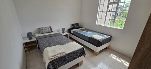 Una pequeña habitación con dos camas y una ventana. en Maison de Vacances Pereybere, en Grand Baie