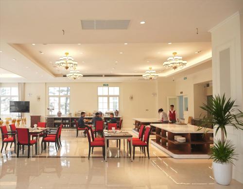 a restaurant with people sitting at tables and chairs at Legend Valley Hotel Ha Nam in Phủ Lý