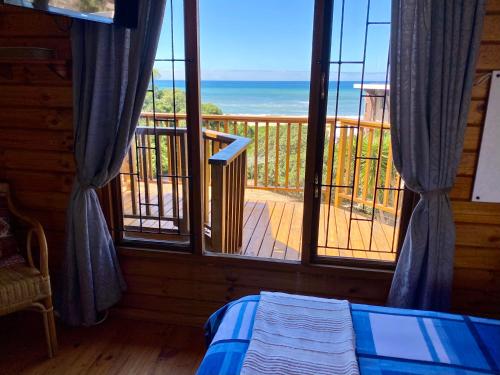 a bedroom with a view of the ocean from a balcony at Shore Enuff - Ocean and Garden View in Jeffreys Bay