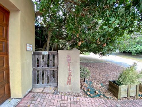 an entrance to a house with a gate and a tree at Shore Enuff - Ocean and Garden View in Jeffreys Bay
