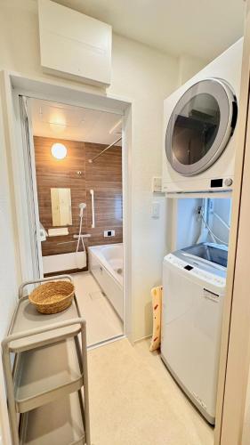 a small bathroom with a microwave on top of a refrigerator at ヤンバルハウスクイナ in Nago