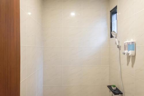 a bathroom with a shower with a phone on the wall at Calma Jawon Villa Jogja in Piyungan