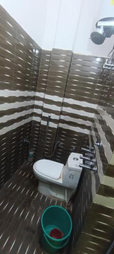 a bathroom with a toilet and a green bucket at Shri Raameshvaram vidya vila in Ayodhya