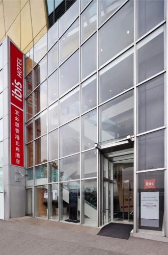 a glass building with a red sign in front of it at ibis Hong Kong North Point in Hong Kong