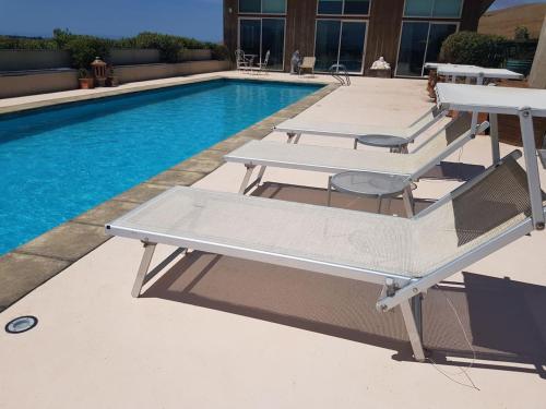 a pool with two tables and a bench next to it at Chagall Suite in an 6-bedroom luxury villa in Blenheim