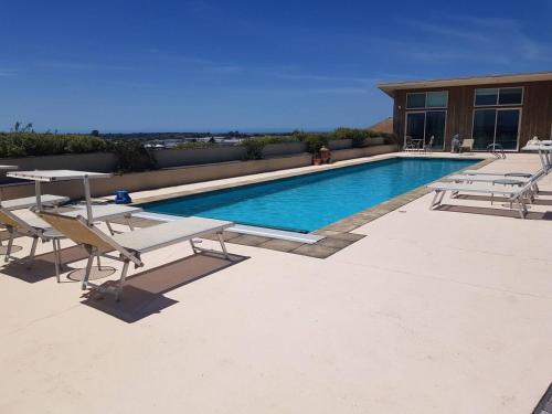a swimming pool with tables and chairs next to a building at Chagall Suite in an 6-bedroom luxury villa in Blenheim