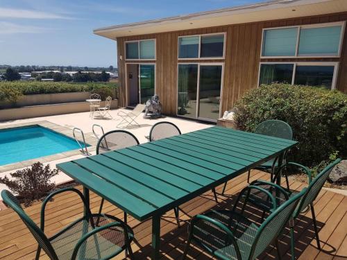 a green table and chairs on a patio with a pool at Chagall Suite in an 6-bedroom luxury villa in Blenheim