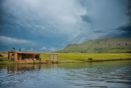 a building sitting on the side of a body of water at Mount Lake Cabins in Harrismith