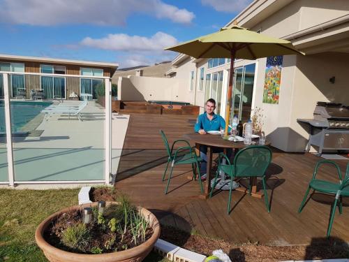 a man sitting at a table with an umbrella at Cloudy Bay Suite in an 6-bedroom luxury villa in Blenheim