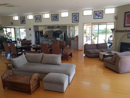 a living room with couches and chairs and a kitchen at Cloudy Bay Suite in an 6-bedroom luxury villa in Blenheim