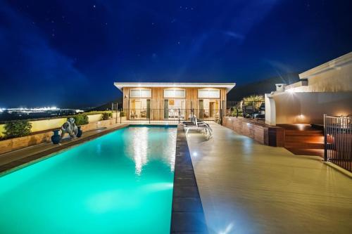 a swimming pool in front of a house at night at Oceanview Suite in an 6-bedroom luxury villa in Blenheim