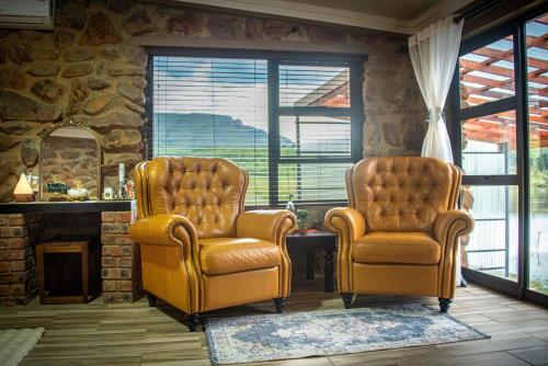 two chairs sitting in a living room with a fireplace at Mount Lake Cabins in Harrismith