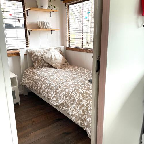 a small bed in a small room with a window at Serendipity Cottage Farm Stay in Jeremadra