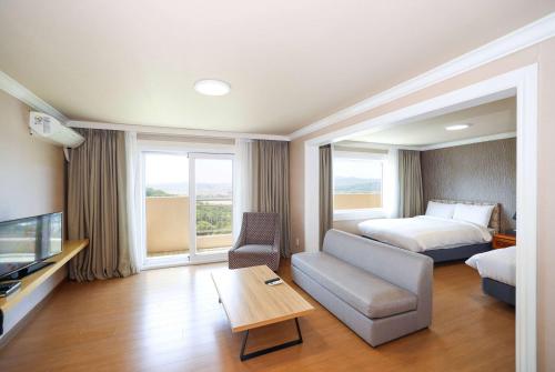 a hotel room with a bed and a couch and a television at La Vie Dor Hotel and Resort, Trademark Collection by Wyndham in Hwaseong