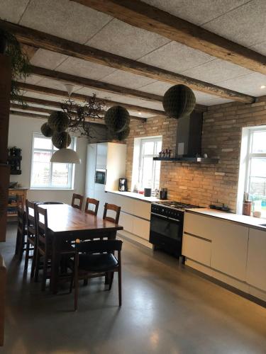 a kitchen with a wooden table and a dining room at Stor villa med privat have in Bredebro