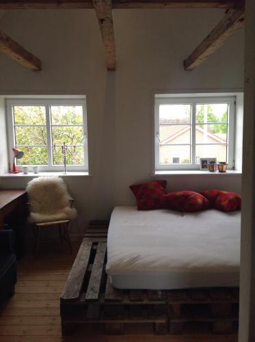 a bedroom with a bed with two windows and a chair at Stor villa med privat have in Bredebro