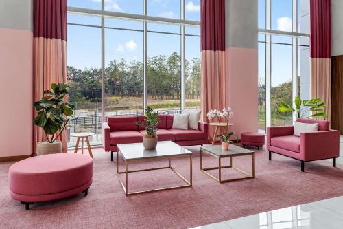 a living room with pink furniture and large windows at Hilton Garden Inn San Jose Airport City Mall in Alajuela City