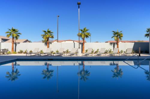 a swimming pool with chairs and palm trees at Homewood Suites By Hilton North Las Vegas Speedway in Las Vegas