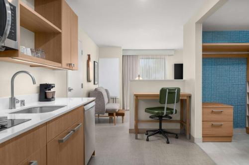 a kitchen with a sink and a green chair at Homewood Suites By Hilton North Las Vegas Speedway in Las Vegas