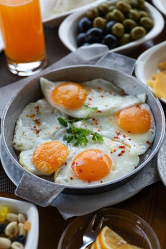three eggs in a pan on a table with other foods at Sheki Palace Hotel in Sheki