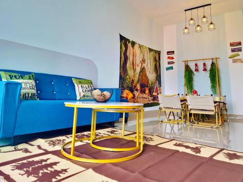 a living room with a blue couch and a table at Leisure Home - 7pax Camping Theme in Kampong Lobok