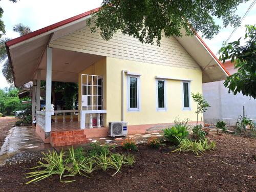 ein kleines gelbes Haus mit einer Veranda in der Unterkunft Baan Suan Thada Thai บ้านสวนธาดา ไทย in Wang Nam Yen