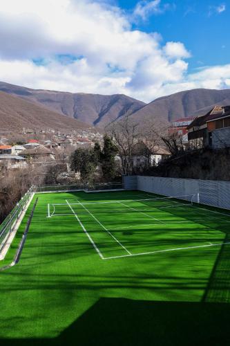 a green soccer field with mountains in the background at Sheki Palace Hotel in Sheki