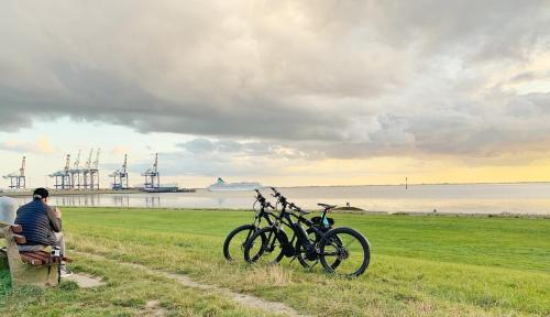a man sitting on a bench next to two bikes at Ferienhaus Nordkönig mit Sauna und Whirlpool in Langen