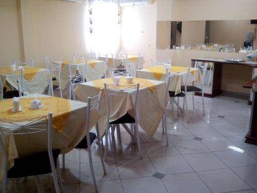 a dining room with tables and chairs with yellow table cloth at Estação Hotel in Castanhal