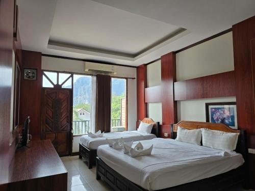 a hotel room with two beds and a large window at Thavisouk Hotel, Vang Vieng in Vang Vieng