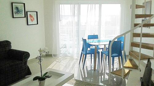 a living room with a dining room table and blue chairs at Vista Marina Residence in Boca Chica