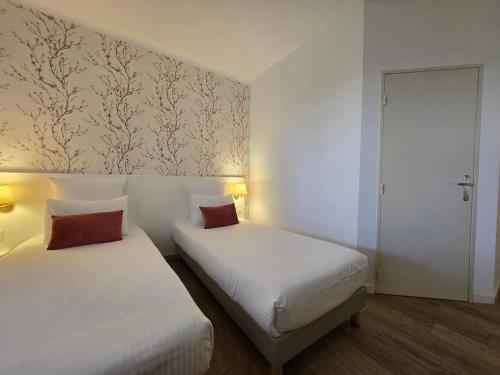 two beds in a room with white walls at Hôtel Le SAINT-GENIÈS in Uzès