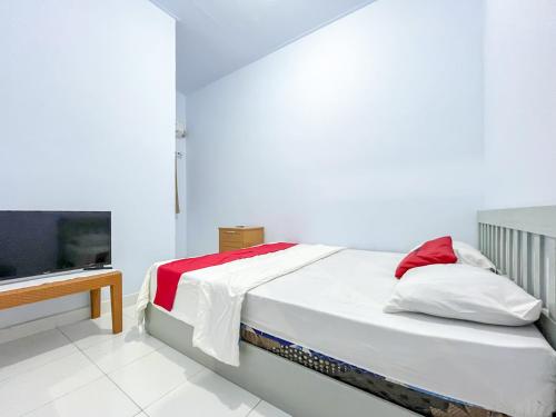 a bedroom with a bed and a flat screen tv at RedDoorz Syariah at Home Ampana Guest House Ampana Kota in Dondo