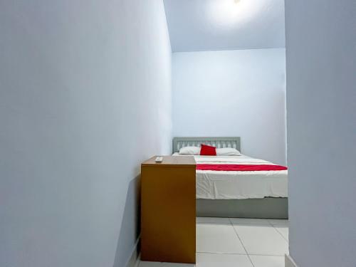 a bedroom with a bed with a red pillow on it at RedDoorz Syariah at Home Ampana Guest House Ampana Kota in Dondo