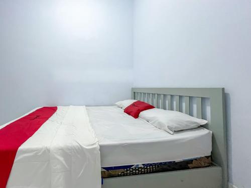 a white bed with red and white pillows on it at RedDoorz Syariah at Home Ampana Guest House Ampana Kota in Dondo