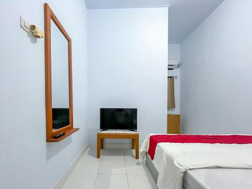 a white room with two beds and a television at RedDoorz Syariah at Home Ampana Guest House Ampana Kota in Dondo