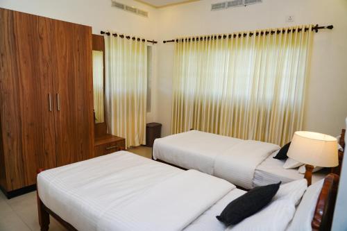 a hotel room with two beds and a window at Wanderville in Vagamon