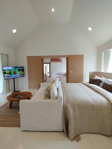 a large white bedroom with a large bed and a couch at Roukh Kiri Khaoyai, The Centara Collection in Pak Chong