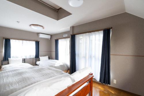 a bedroom with two beds and two windows at The Nekozane HAUS in Urayasu