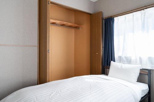 a small bedroom with a bed and a window at The Nekozane HAUS in Urayasu