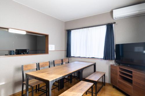 a dining room with a table and chairs and a television at The Nekozane HAUS in Urayasu