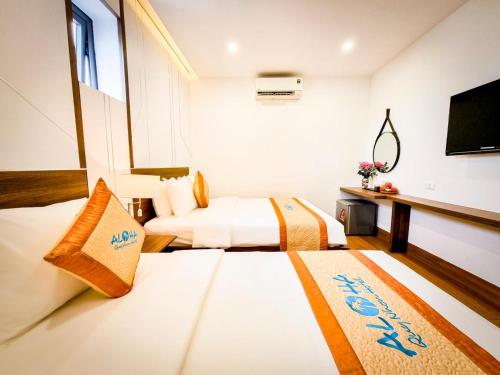 a hotel room with two beds and a flat screen tv at Aloha Hotel in Quy Nhon