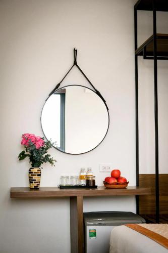 a mirror hanging on a wall above a table with fruit at Aloha Hotel in Quy Nhon