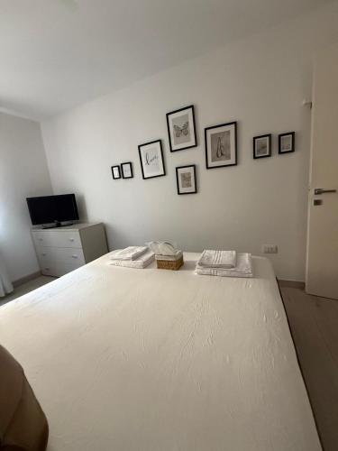 a bedroom with a large white bed with pictures on the wall at Suite Piazzetta Vigo in Chioggia