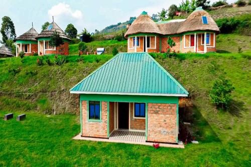 a small house with a green roof on a hill at Nyamunyonyi Lake Resort in Kabale