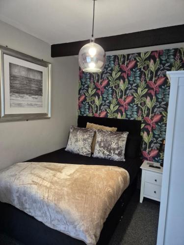 a bedroom with a bed with a floral wallpaper at Rugby Coach House, Central location, 5 star rating in Rugby