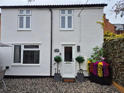 a white house with potted plants in front of it at Rugby Coach House, Central location, 5 star rating in Rugby