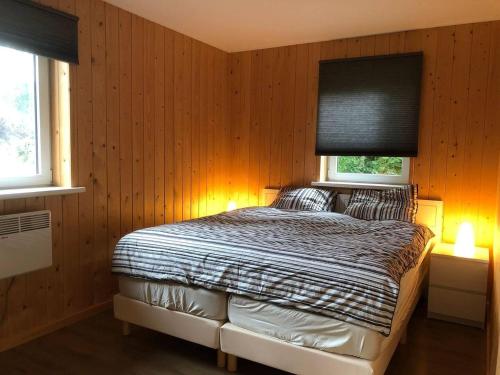 1 dormitorio con 1 cama con paredes y ventanas de madera en Bungalow Lijsterbes | 4 personen - Vakantiepark De Kremmer, en Gasselte
