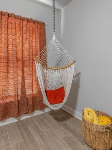 a hammock hanging in a room with a basket of bananas at Groovy, New & Modern! Tv in each room in Shreveport