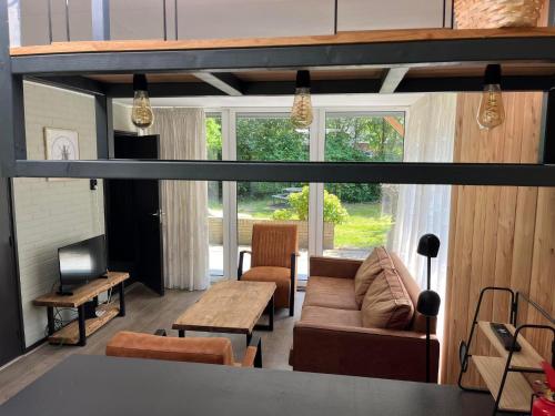 a living room with a couch and a table at Bungalow Zandzegge | 4 personen - Vakantiepark De Kremmer in Gasselte